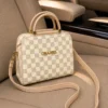 Beige checkered women’s handbag with shoulder strap on car seat