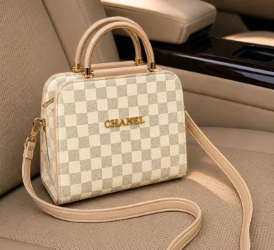 Beige checkered women’s handbag with shoulder strap on car seat