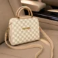 Beige checkered women’s handbag with shoulder strap on car seat