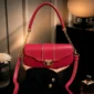 Red and pink women’s handbag with gold-tone hardware, top handle, long adjustable shoulder strap, and front clasp closure.