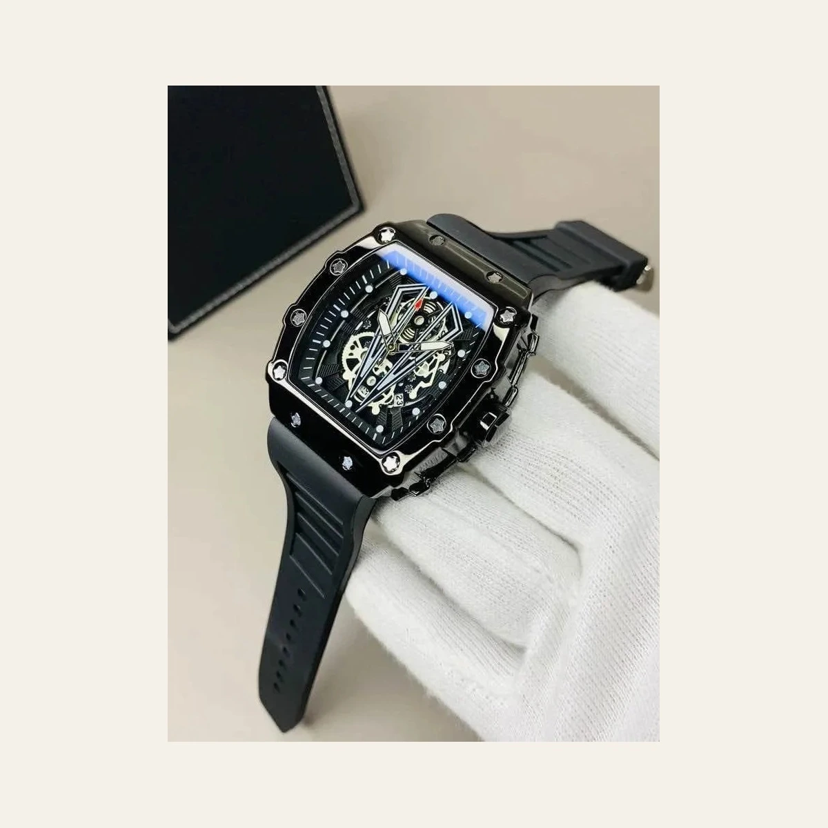 Black luxury skeleton watch with a detailed mechanical dial, rubber strap, and white glove against a beige background.